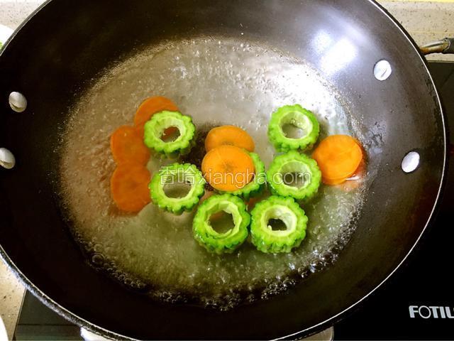 锅里水烧开后加一勺盐，将苦瓜和胡萝卜焯水一分钟。