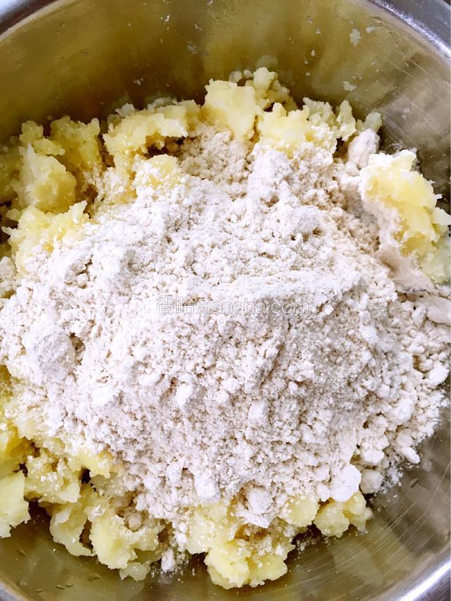 在土豆里加适量的莜面，用手轻轻揉搓，使莜面和土豆拌均匀就好，不要揉成一块，如图。
