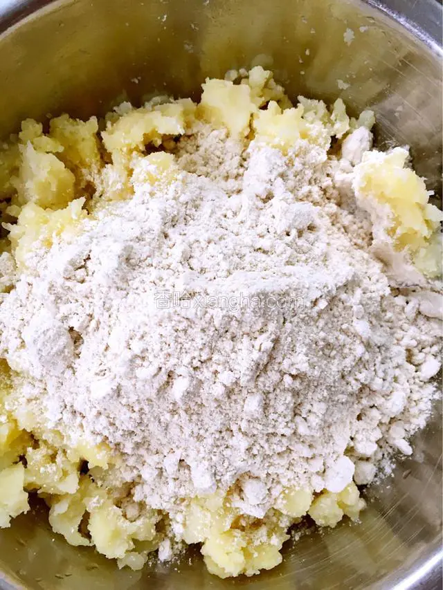 在土豆里加适量的莜面，用手轻轻揉搓，使莜面和土豆拌均匀就好，不要揉成一块，如图。