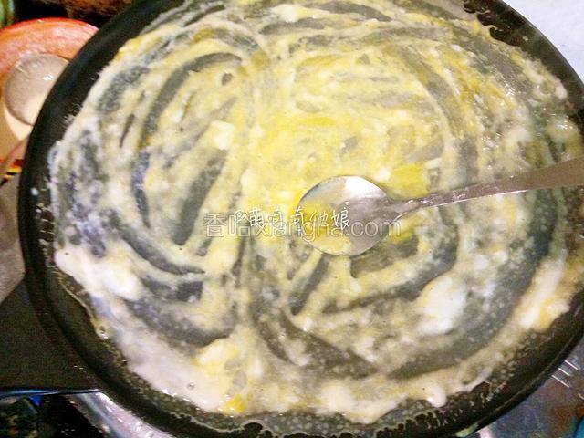 开大火加热至饼皮变白半熟状态，转小火，磕入一个鸡蛋，用勺子戳破蛋黄并抹开。