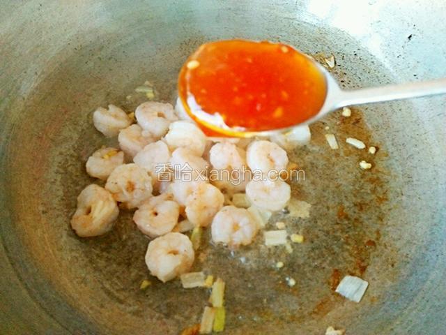 虾仁翻炒变色后放入2汤勺的泰式酸辣酱和一点盐，加一点饮用水翻炒均匀。