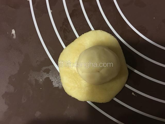 取一个油皮按扁，放入一个酥皮，包紧收口。