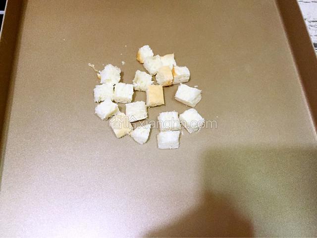 先把小片的土司切成丁，放进烤盘中