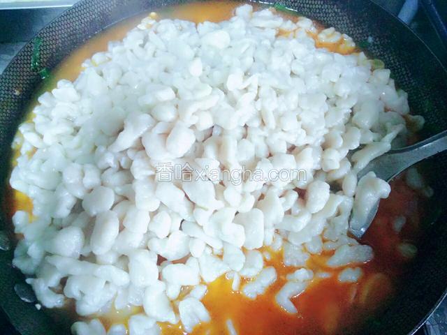 将煮好的麻食用漏勺舀到菜锅里