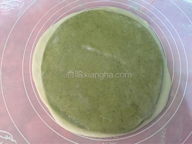 绿色面团擀成比白色面团小一圈的薄片，绿色面团和白色面团之间抹点水用擀面杖继续擀薄，让白色面团和绿色面团更紧密的结合在一起
