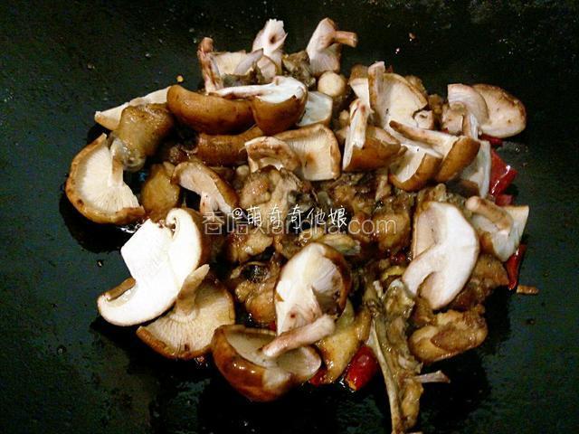 加入鸡肉和香菇，转大火翻炒至香菇微变软。