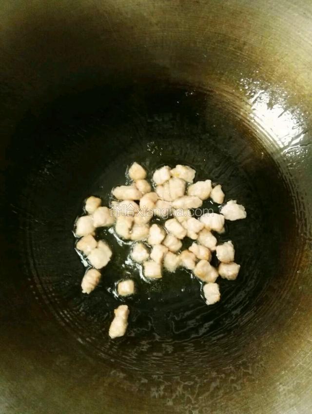 待锅内油烧热，先把肉丁放进去中火快速翻炒至五成熟，然后装盘备用。