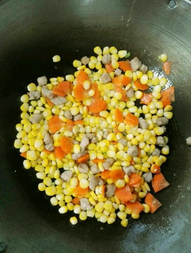 接着加入刚才装盘的红萝卜、玉米、肉丁，一起中火翻炒一下。