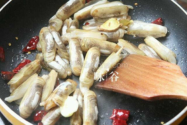 锅内热油下姜和干辣椒爆香后倒入蛏子翻炒