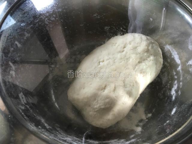 用手把搅拌好的面粉揉成光滑的面团，盖保鲜膜醒30分钟。