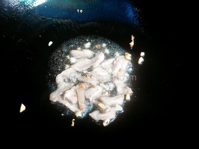 锅中加少量的油放入蒜和辣椒煸香后放入瘦肉片，煸炒至断生