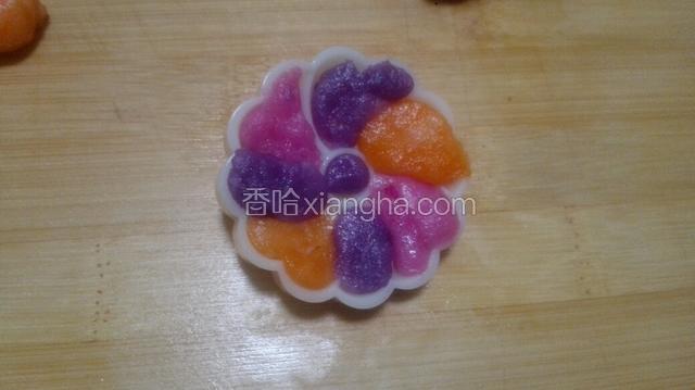 将刚才调好带颜色的小面团，每个取一点点摁入月饼模具的花片上，再将花片放入月饼模具中！