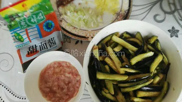 茄子洗净切4～5cm长条，加盐腌制10分钟后挤出水份；小红椒切段，葱姜蒜切末。