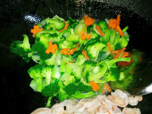 把虾仁推一边，倒入西兰花翻炒。