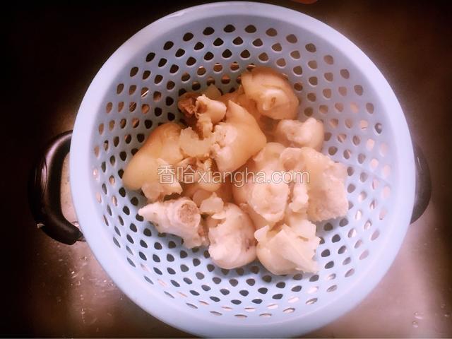待锅内水煮沸时，将猪蹄捞出，倒入篮子内，沥干水份