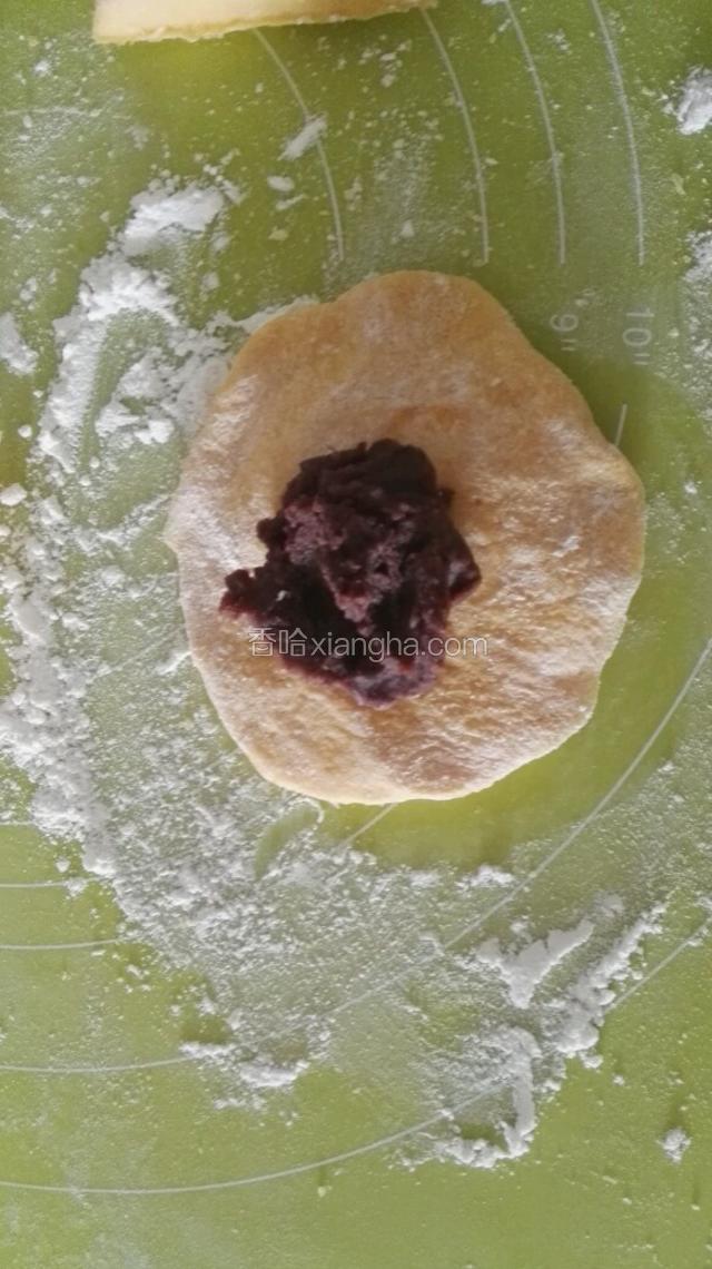 取一团擀成中间厚，边缘薄的面皮，中间放入红豆沙