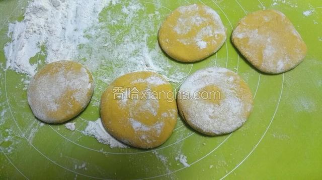 南瓜面团揉出气泡，分成40克一个的小面团，压瘪，擀成圆形。