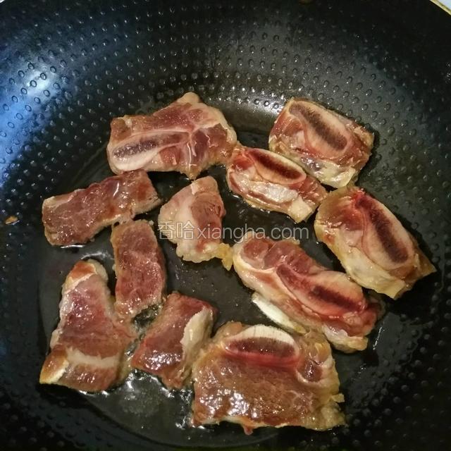 取不粘锅倒入适量的油，放入腌制的牛仔骨稍微煎七分熟就可以了，中间记得翻面