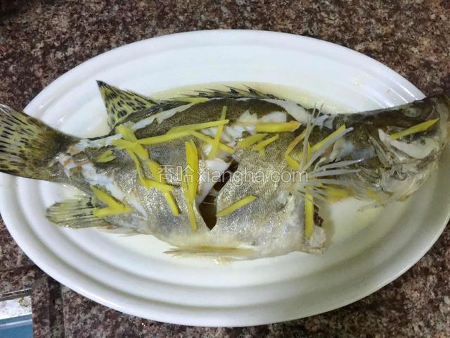 蒸好的鱼拿出来把盘子里蒸出来的水倒出一半。