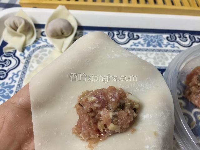 把肉馅放在云吞皮靠身体的这一边。