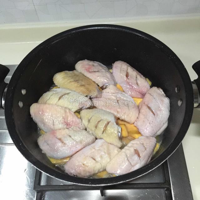 在红薯上面摆上鸡翅，盖上锅盖焖煮20分钟