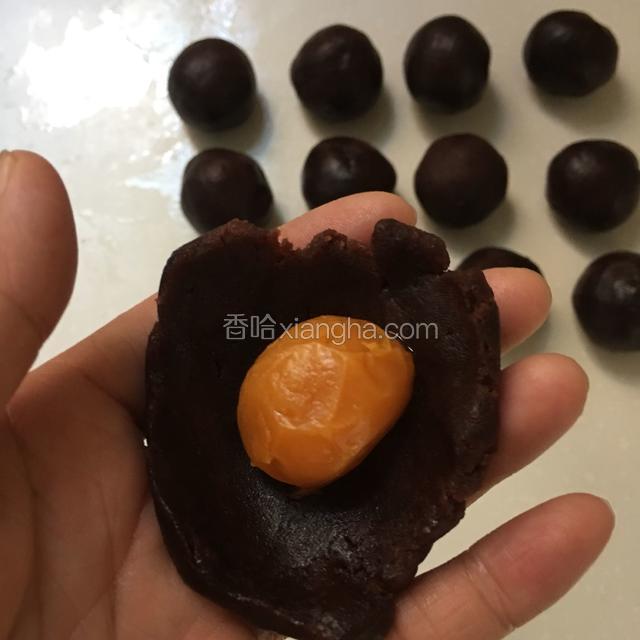 醒面期间我们来做馅料，取适量豆沙按扁把蛋黄包住