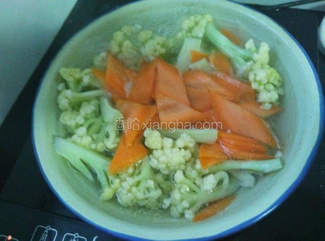 把花椰菜下开水里煮一分钟，加入胡萝卜再煮一分钟。
