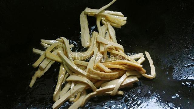 重新洗锅，锅烧热倒入油，微热倒入豆腐干丝。
