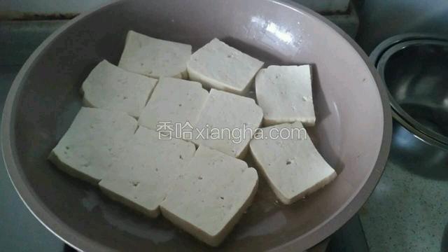 豆腐切成厚片，平底锅加入少许油放入豆腐