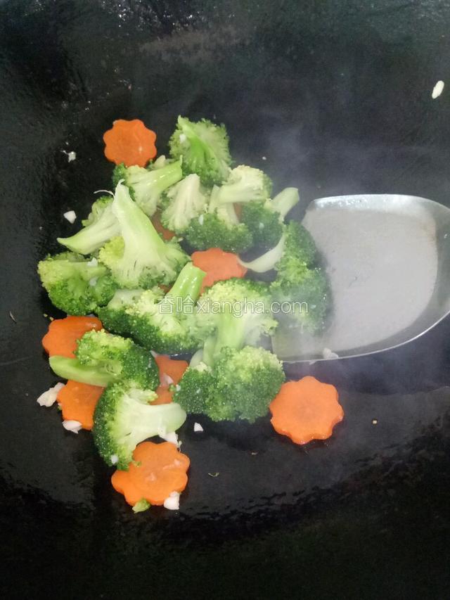 倒入西兰花和胡萝卜翻炒至八成熟，装起待用。