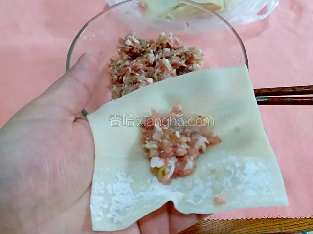 第一步取一张馄饨皮，把虾肉馅放在皮中间。