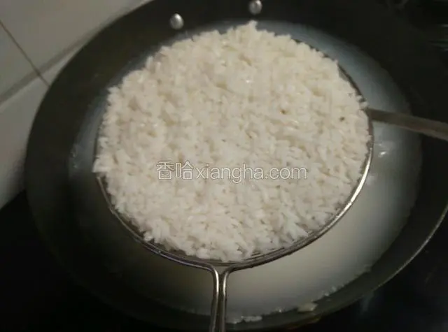 用漏勺把米饭捞出控水（剩余的米汤可以留起来喝，很甘甜，或者留一些饭粒在锅里熬粥，口感特别好）。