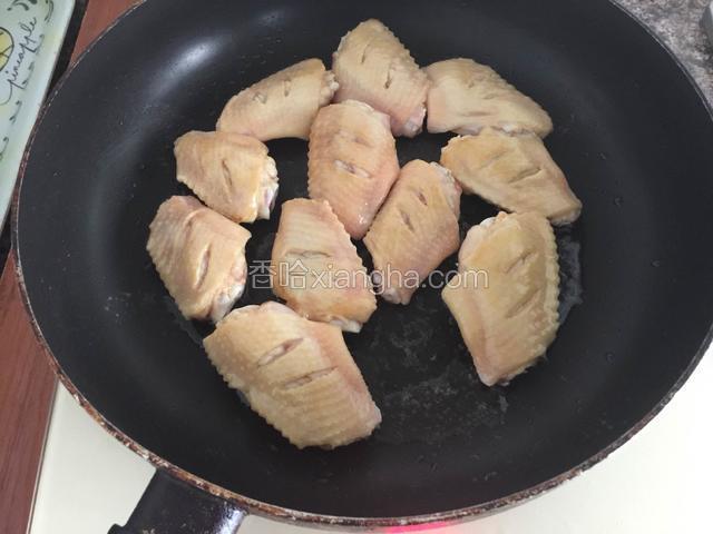 平底锅烧热后倒入适量的花生油将鸡翅放入，调小火慢慢煎。