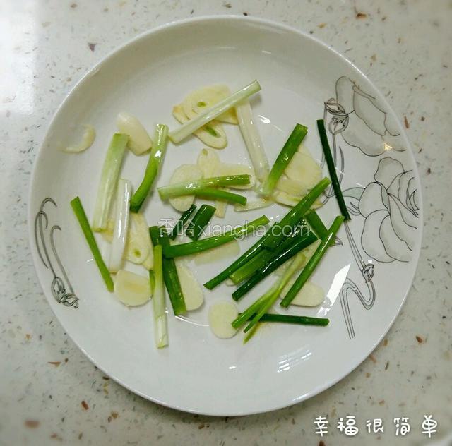 取出蒸鱼盘，盘底垫上适量的蒜片， 姜片，葱段。