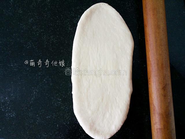 松弛好的面团用擀面丈擀成椭圆形。