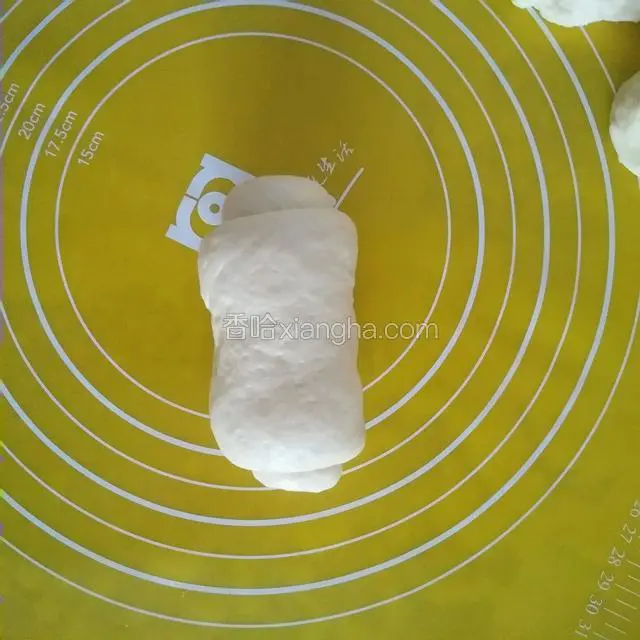 这时把面包桶里的搅拌叶拿出来，把面团分成三等份用擀面杖擀成大舌头状卷起来