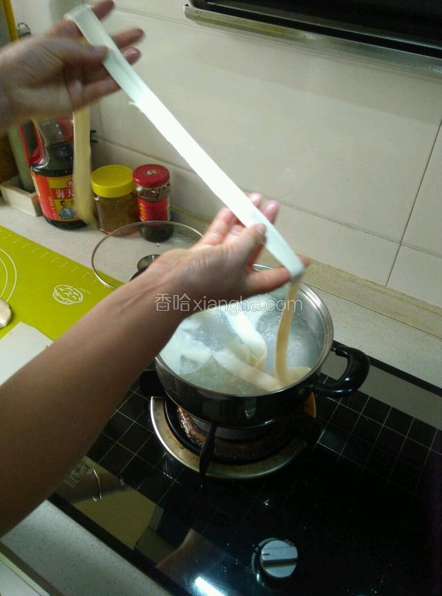 锅里水烧开，从面片中间切一刀（就是擀面杖压的那一道）拿起面的两头往两边拉扯，放进锅里，薄厚自己掌握喜欢薄的就稍微扯薄点