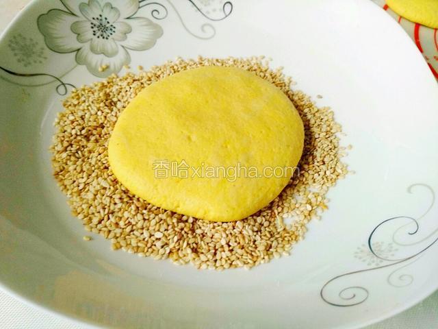 饼子放芝麻盘里，两面沾满芝麻。然后按实芝麻，防止炸时掉芝麻。