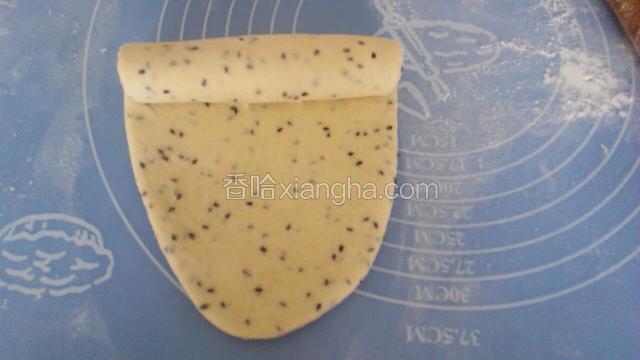 取一个面团，用面轴擀成牛舌状，然后自上往下卷起来