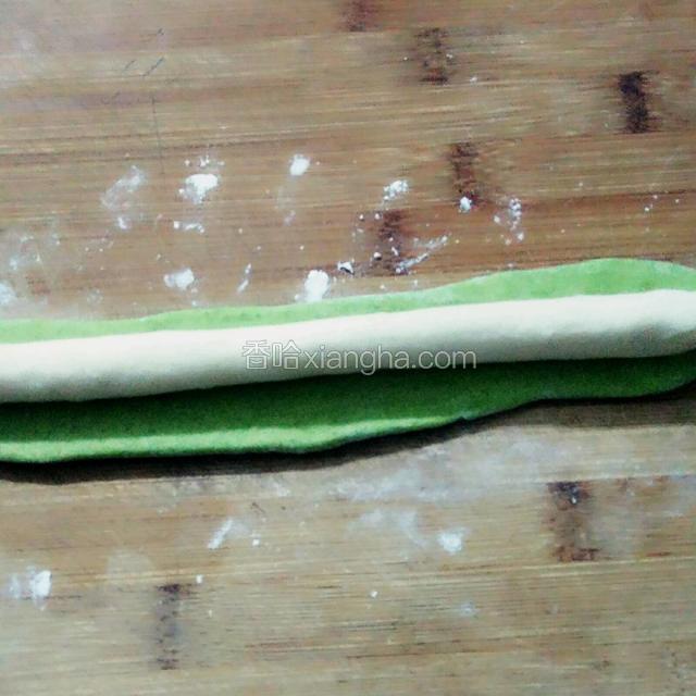 把绿色的面条擀平一些裹住白色面条