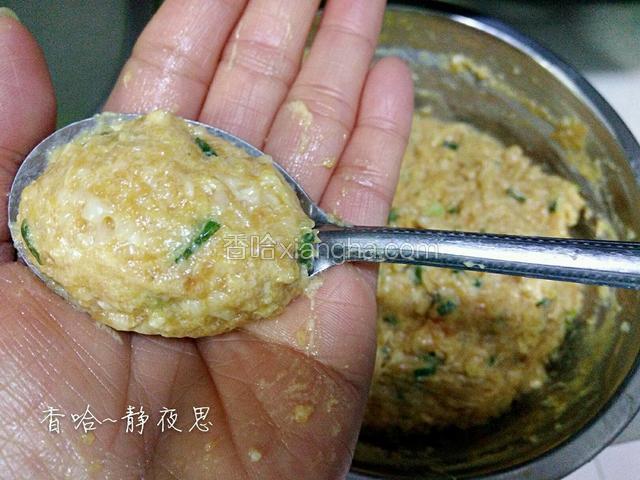 右手拿勺子挖一大勺拌好的肉泥，把肉泥来回在左手掌心摔打几下