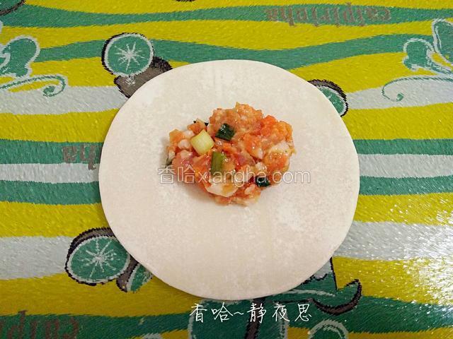 取一张饺皮，在中间放入适量肉馅