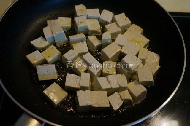平底炒锅中倒适量油，油温热时，倒入豆腐块，平铺在锅底；