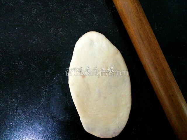 收口朝下压扁，并用擀面丈擀成椭圆形，可以擀长点。