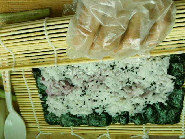 用竹帘带动紫菜，卷成形。紫菜边沿沾点水。