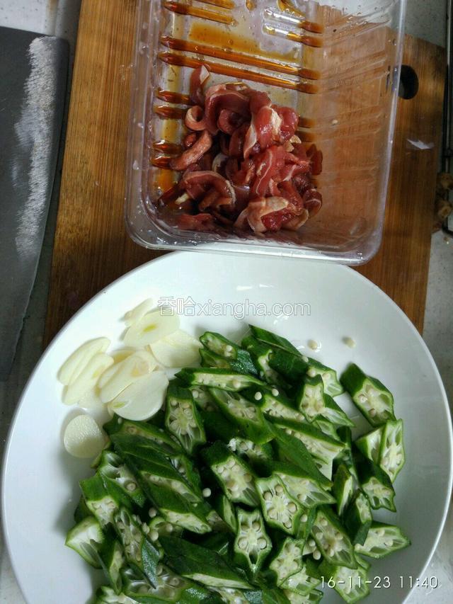 准备下食材，秋葵去除尾、头部，切成点厚度的菱形！肉切条，用适量的料酒，生抽，生粉腌制十五左右，大蒜切片备用！