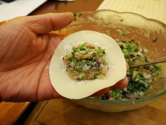 取饺子皮一张，中间放上饺子馅儿，这次饺子皮是买的现成的，需要在周围沾上清水，自己擀的饺子皮就可以省去这一步。