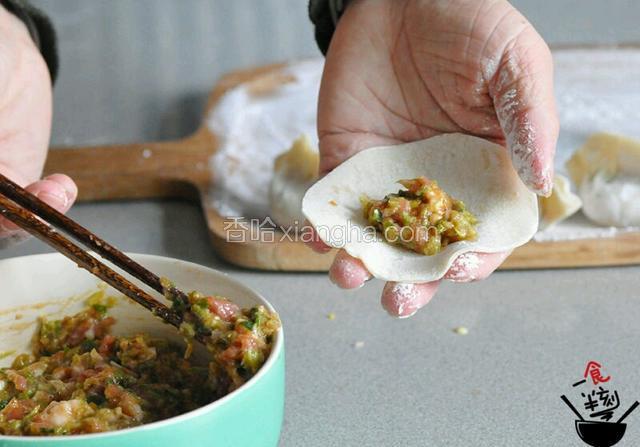 饺子皮放入适量的肉馅，将饺子皮对折，用双手和大拇指和食指捏成型