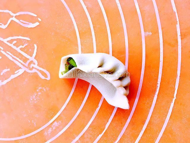 然后左手食指往后推一下，右手食指和拇指捏一个褶子，以此类推，捏好其它褶子，右手拇指始终沿着里边的面皮慢慢往前移动