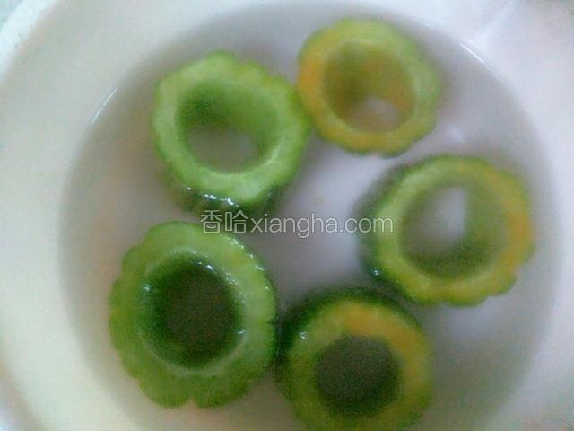 将苦瓜放进水中冲两次去掉盐，再将它捞起沥干斜放，在周围放上少量鸡精。（放鸡精的方法跟步骤三放盐的方法一样）